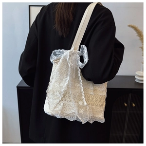 Close-up of white lace tote bag with large bow detail and layered floral textures