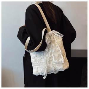 Detail of elegant beige floral lace tote bag featuring ruffled mesh trim and leather straps