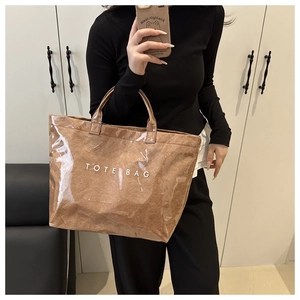 Detail of a brown tote bag featuring waterproof PVC coating and bold white TOTE BAG lettering