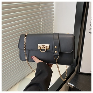 Detail of black faux leather rectangular bag with golden D-ring twist lock and chain strap