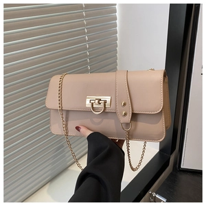 Macro detail of beige leather crossbody bag with golden rectangular turn-lock and chain