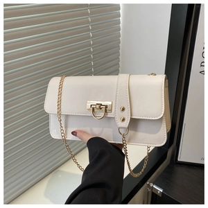 Detail of cream baguette bag with gold metal turn-lock and elegant chain shoulder strap