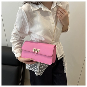 Close-up of bright pink shoulder bag featuring a metallic lock and golden chain strap