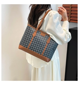 Detail showing the gray monogram tote bag with brown leather straps worn on shoulder