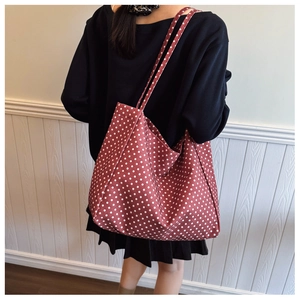 Detailed view of red polka dot canvas tote bag worn by model on shoulder