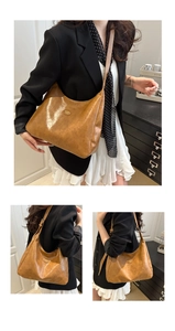 Detail showing vintage brown PU leather texture and metal logo plaque on hobo bag