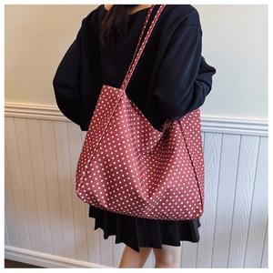 Detail of red polka dot canvas tote bag shown on model for size and drape reference