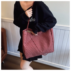 Detail of red canvas tote bag with white polka dots showing the shoulder strap design