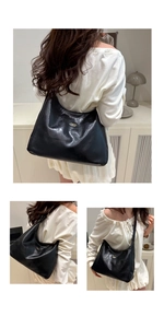 Detail view of black soft leather tote bag showing a sleek oval fashion brand emblem