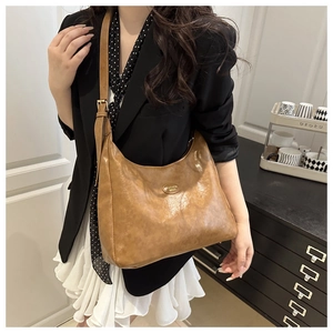 Detail of hobo shoulder bag in brown faux leather with vintage texture and metal logo