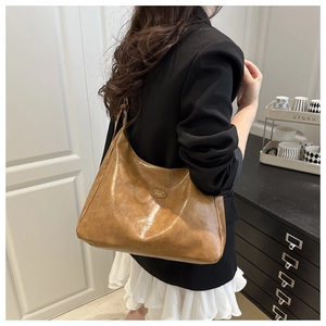Close-up of a brown vintage crescent tote bag with FASHION BAGS leather patch detail