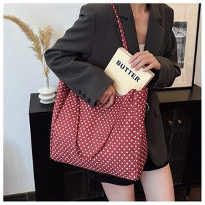 Polka dot canvas tote bag shown on a shoulder in a stylish minimalist interior setting