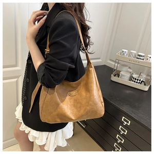 Close-up of brown vintage leather tote with adjustable strap and oval fashion plaque