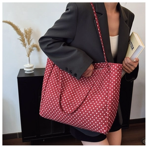 Detailed view of red polka dot canvas tote bag worn by a model in a stylish setting