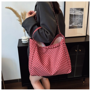 Detailed view of red polka dot canvas tote bag worn by a model in a modern interior