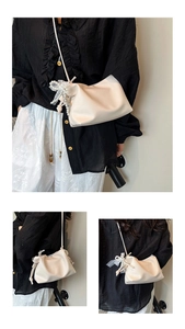 Detail of cream pleated cloud bucket bag featuring pearl and lace bow decorative pendant