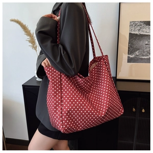 Detailed view of red canvas tote bag with white polka dots on a stylish model