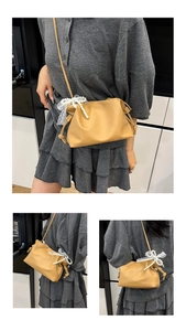 Detail of ginger yellow ruched cloud bag with pearl strap and white lace bow decoration