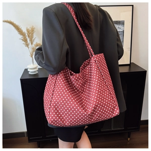 Detailed back view of a person wearing a large capacity red polka dot canvas tote bag