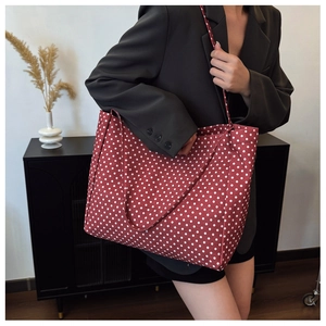 Detail of red canvas tote bag with white polka dots featuring large capacity and straps