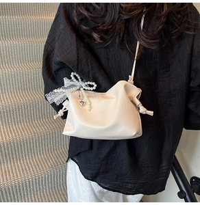 Detail of cream white leather cloud bag with pearl bow, lace trim and heart pendant