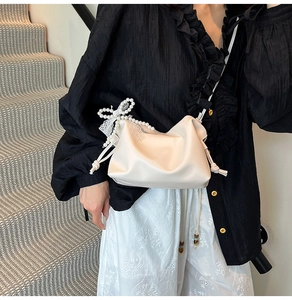 French style cream cloud bag with pearl strap and white lace bow on model