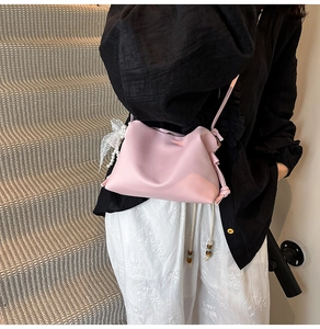 Pink shoulder bag detail with pearl and lace bow charm on soft leather texture