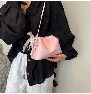 Close-up of pink cloud bag featuring white lace bow and elegant pearl charms