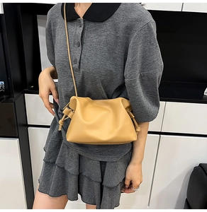 Detail of camel leather drawstring crossbody bag with side knots and slim shoulder strap