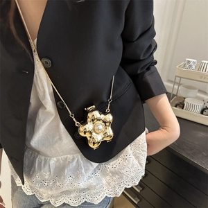 Goldene Mini-Umhängetasche in Blumenform mit Perle und Metallkette auf schwarzem Blazer