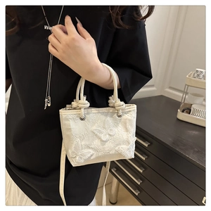 Détail du sac seau brodé en dentelle blanche avec ornements de papillons en 3D