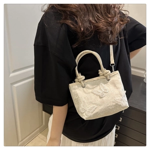 Détails de la broderie papillon 3D et de la dentelle sur un sac seau crème chic