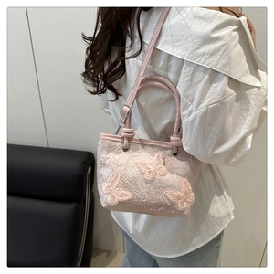 Détail du sac en dentelle rose clair avec papillons 3D et poignée en cuir élégante