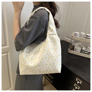 Large floral canvas tote bag with bow detail shown on shoulder in a home setting