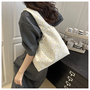 Detail view of floral canvas tote bag showing yellow flower pattern and side carry style