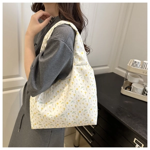 Floral canvas tote bag with yellow blossoms shown on shoulder in a cozy interior