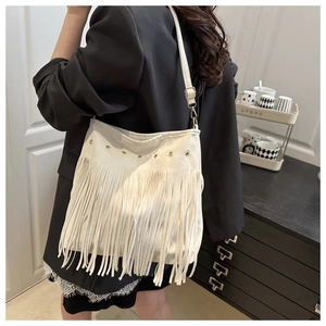 Detail view of a white Bohemian tassel shoulder bag with gold metal eyelets and long fringes