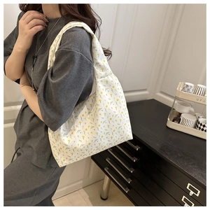 Detail of floral canvas tote bag featuring yellow daisy print on a white shoulder strap