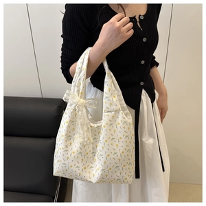Detail of floral canvas tote bag with delicate white lace bow accent and yellow flower print