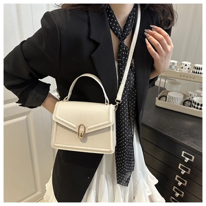Chic cream leather crossbody bag with gold buckle styled with a black blazer