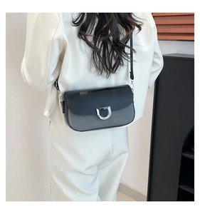 Detail of minimalist gray fabric and black leather crossbody bag with silver D-buckle