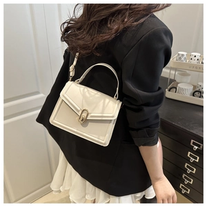 Detail showing creamy white square leather crossbody bag with golden oval metal buckle