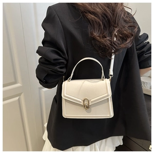 Beige small square handbag with gold buckle worn with a black blazer and white skirt