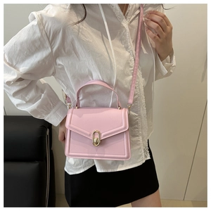 Detail van een roze crossbodytas met gouden ringsluiting gedragen door een model