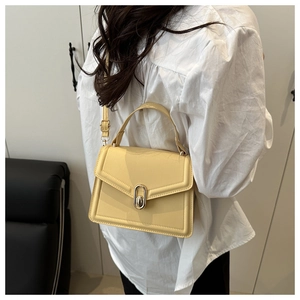Detail van gele crossbodytas met gouden draaisluiting en verstevigd handvat aan de top