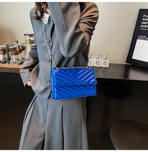 Detail of royal blue leather shoulder bag with classic V-shaped quilting and silver chain