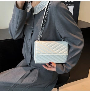 Close-up of white quilted leather texture and silver chain strap on crossbody bag