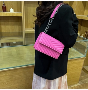 Hot pink quilted crossbody bag with V-shaped stitching and silver chain strap detail