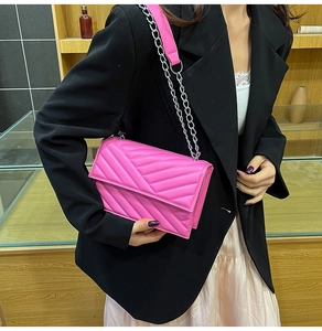 Detail of fuchsia V-quilted shoulder bag with silver chain strap on black blazer