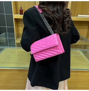 Detailed view of magenta quilted crossbody bag with silver chain strap and flap design
